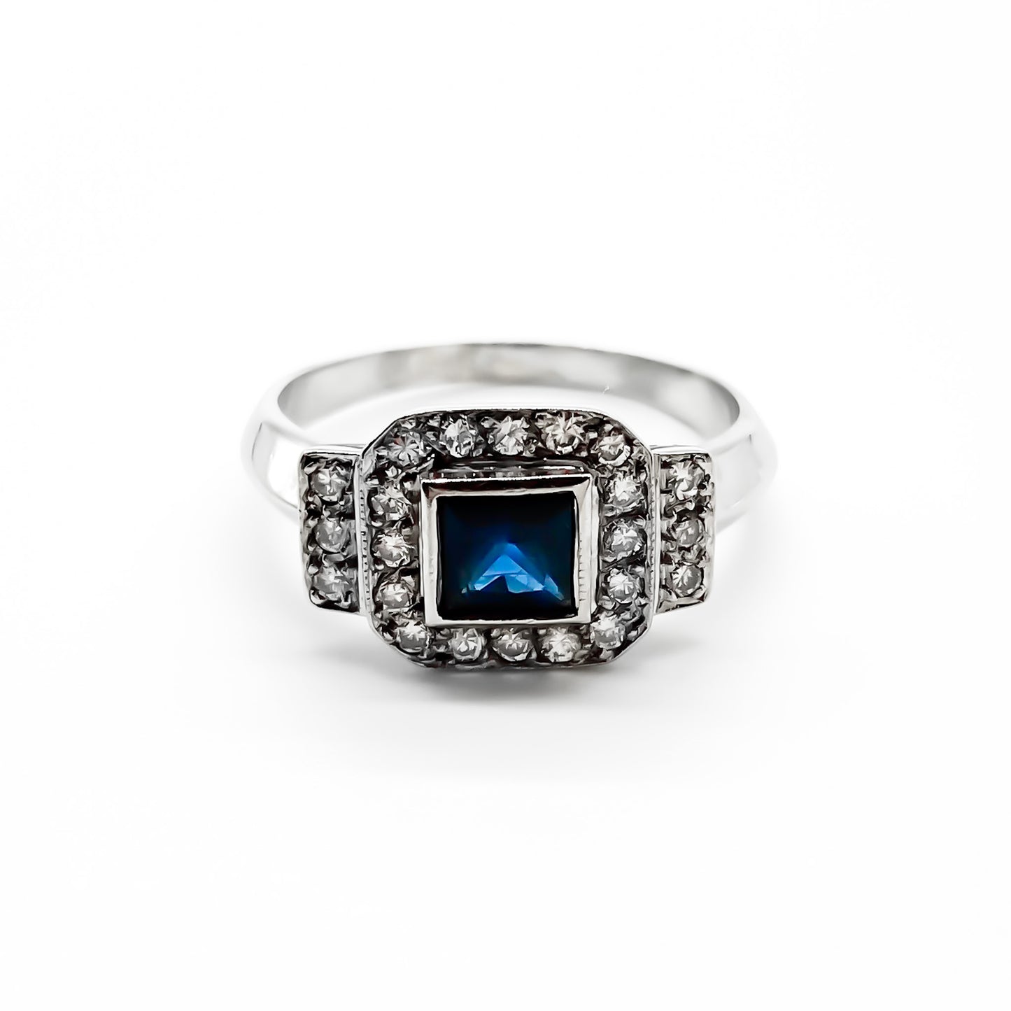 Stunning 18ct white gold ring set with a princess cut sapphire and twenty-two small sparkling diamonds.