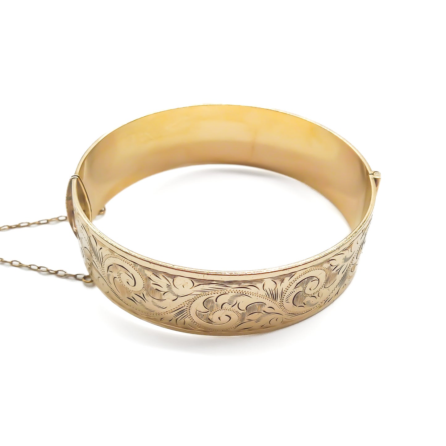 Beautifully engraved 9ct yellow gold bangle with a bronze core. Safety chain attached. Circa 1940’s