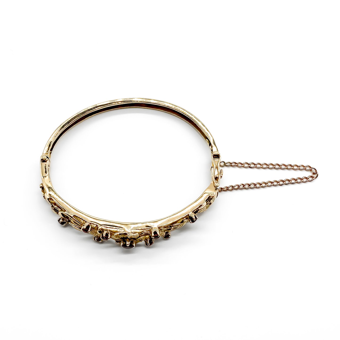 Beautiful 9ct rose gold bangle set with nine faceted garnets in a lovely floral design. Gold safety chain attached.