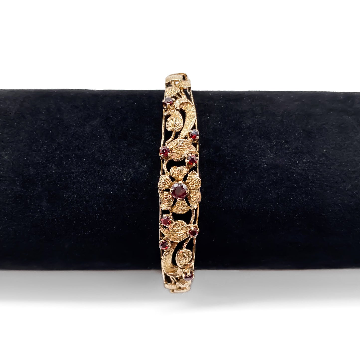 Beautiful 9ct rose gold bangle set with nine faceted garnets in a lovely floral design. Gold safety chain attached.