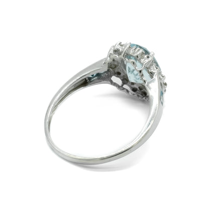 Classic 9ct white gold ring set with a beautifully faceted, light blue aquamarine surrounded by twelve tiny diamonds and two princess cut aquamarines on each shoulder.