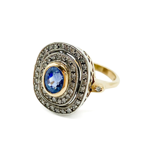 Beautiful Art Deco 14ct white and yellow gold ring set with an oval cornflower blue sapphire surrounded by two rows of small diamonds, as well as a small diamond on each shoulder. Italy