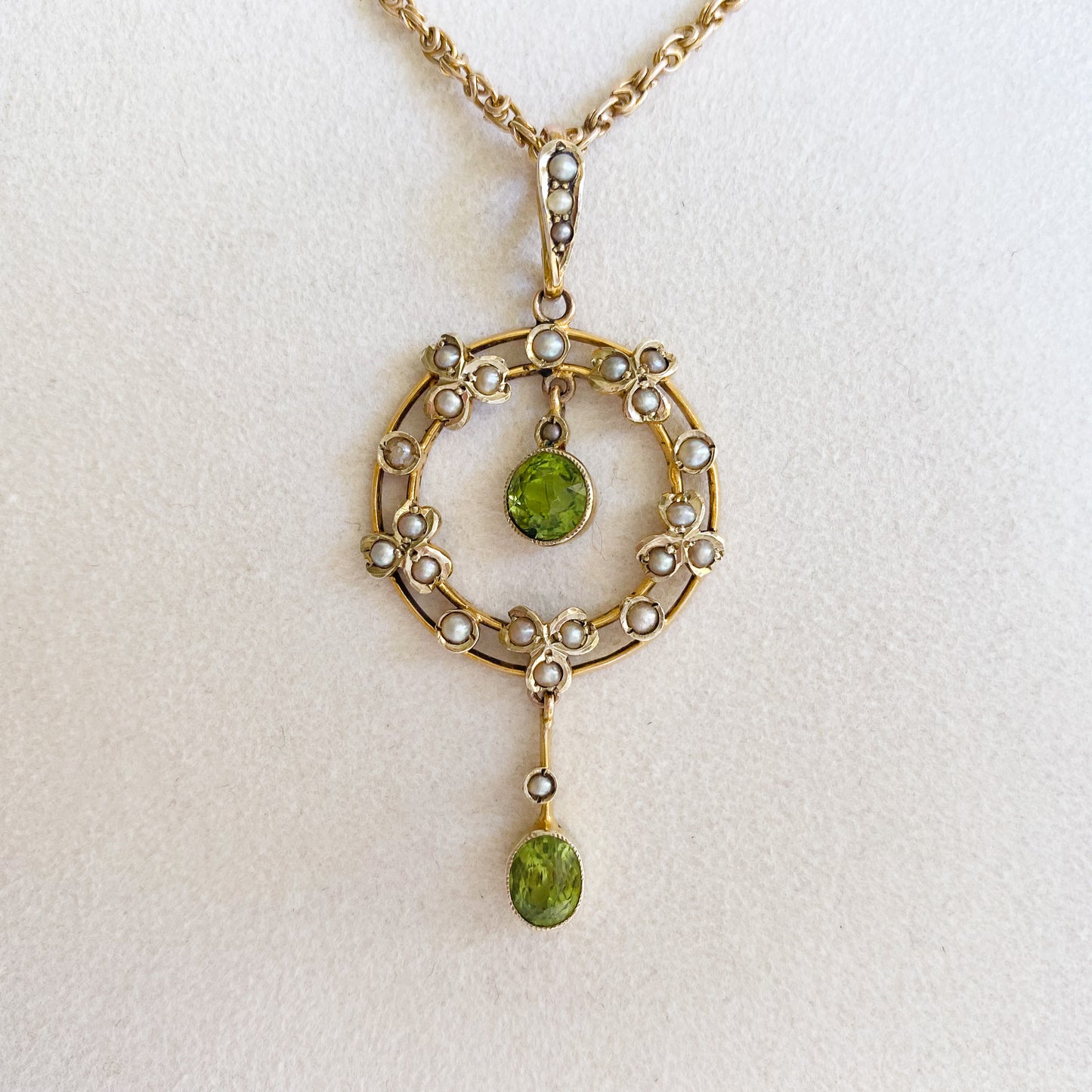 Stunning Edwardian 9ct gold dangling pendant set with two beautifully faceted green peridots and twenty-four tiny seed pearls. On an original 9ct gold fancy link chain. 