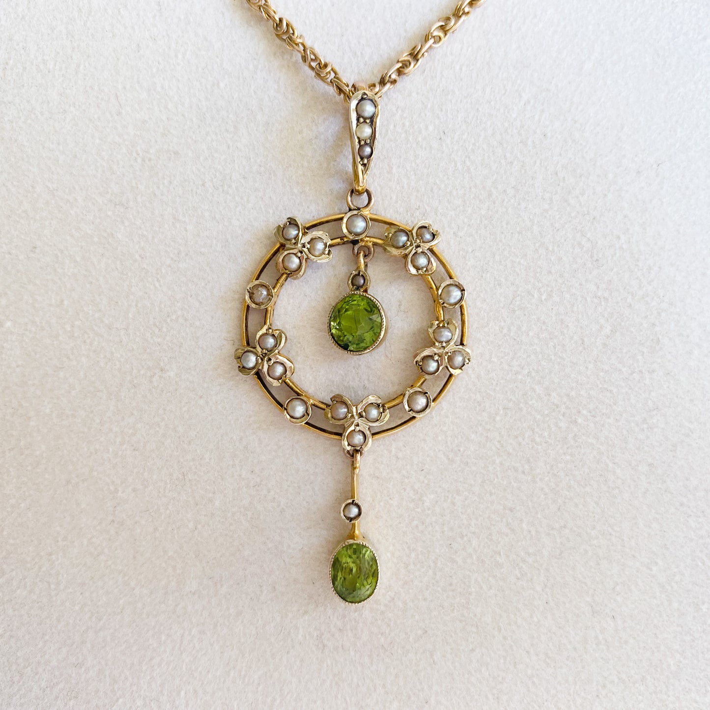 Stunning Edwardian 9ct gold dangling pendant set with two beautifully faceted green peridots and twenty-four tiny seed pearls. On an original 9ct gold fancy link chain.