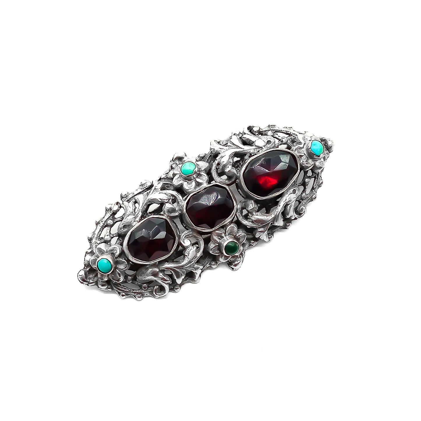 Intricate sterling silver Arts and Crafts brooch set with three large faceted Bohemian garnets and four small turquoise stones. Zoltan White & Company.