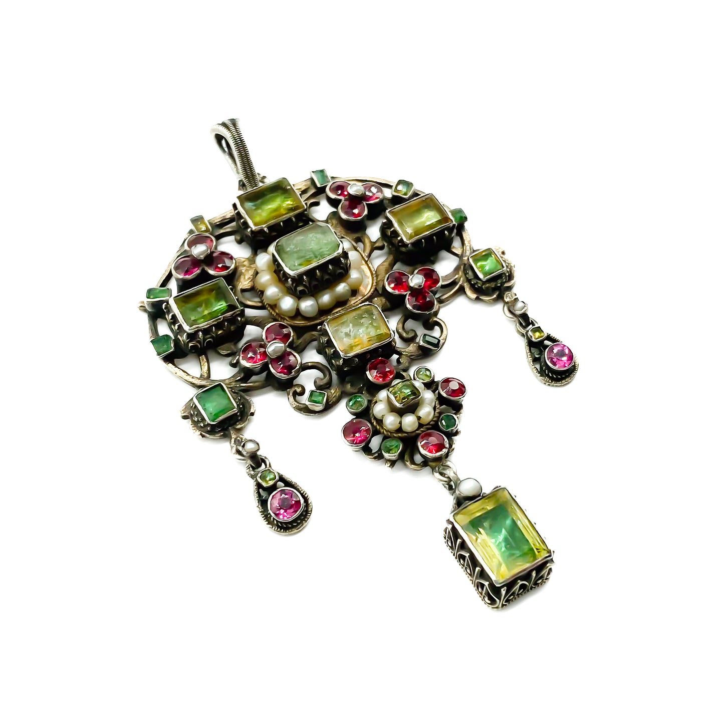 Very ornate silver gilt Austro-Hungarian Festoon pendant set with garnets, seed pearls, emeralds and other green stones. Pendant has beautiful engraving and floral detail. Circa 1890