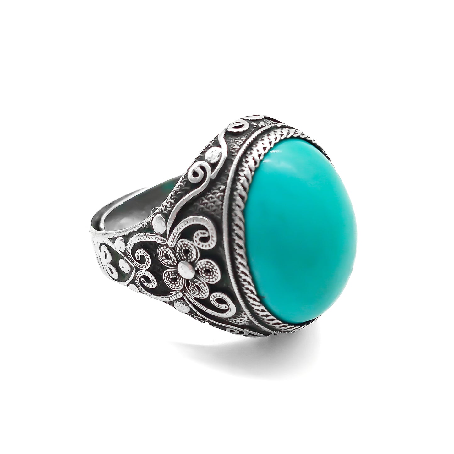 Silver ring set with a beautiful cabochon turquoise stone and ornate filigree embellishment.