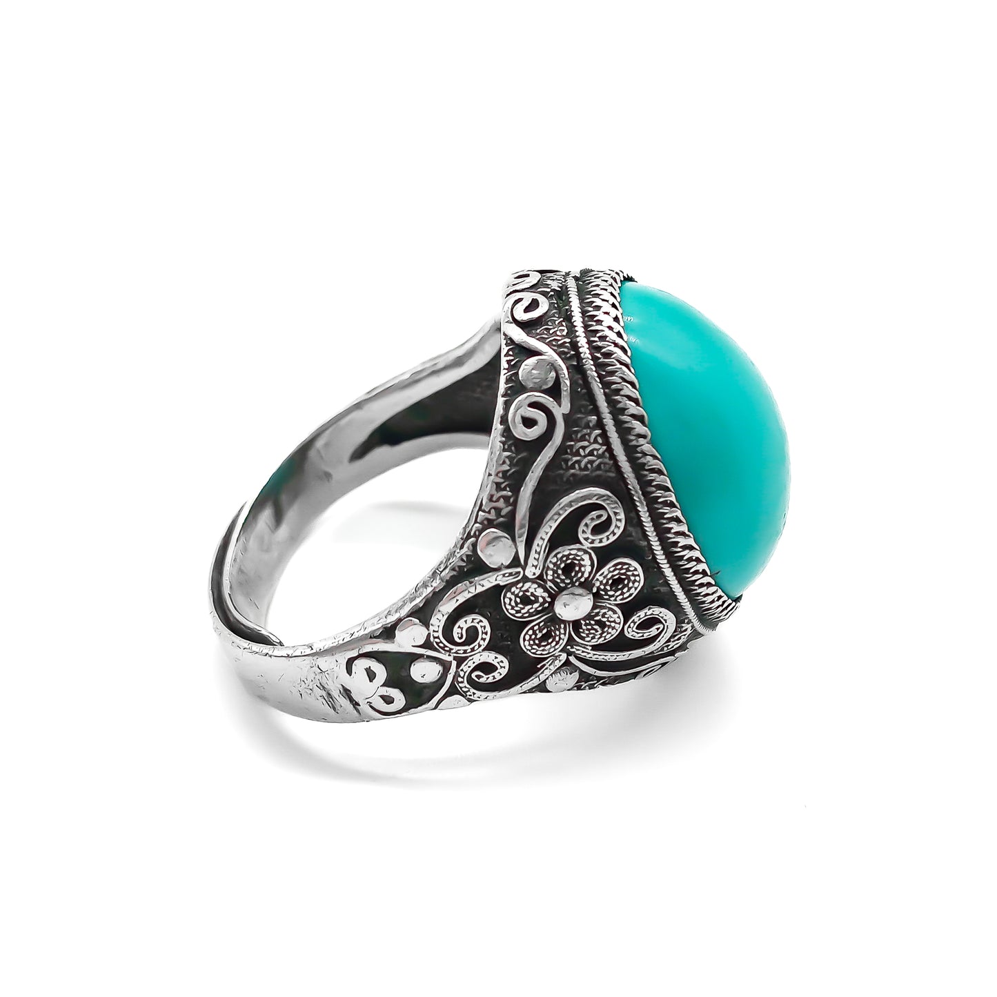 Silver ring set with a beautiful cabochon turquoise stone and ornate filigree embellishment.