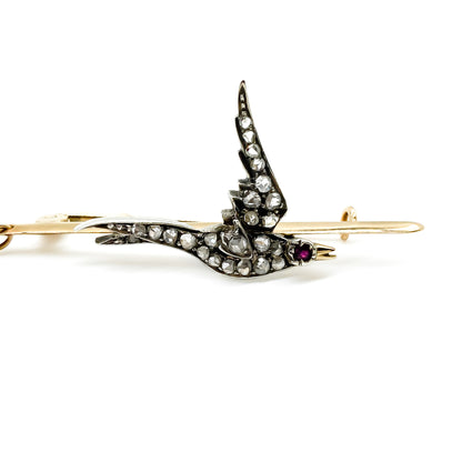 Exquisite Victorian 15ct rose gold bar brooch depicting a bird, set with twenty-three mine cut diamonds and a ruby eye. Gold safety chain attached.