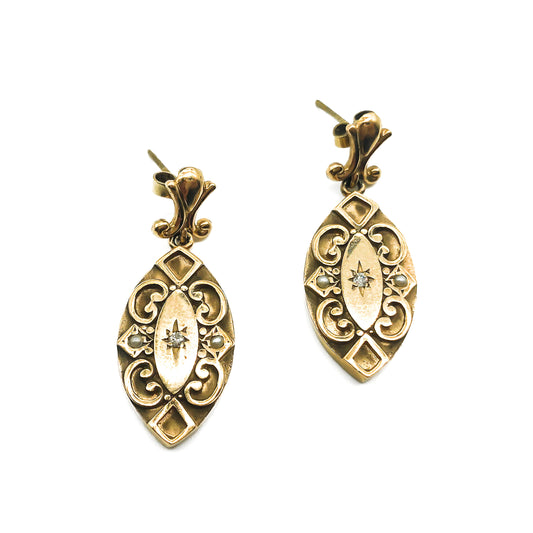 Exquisite 9ct rose gold earrings with lovely scroll work, each set with a single diamond and two seed pearls.