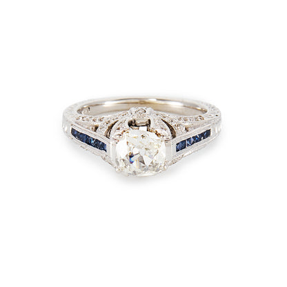 Magnificent 14ct white gold ring, set with a 0.70ct Old-European-Cut diamond, as well as seven princess-cut sapphires on each shoulder. The ring also features a diamond encrusted gallery. A valuation from The Gem Lab is included.