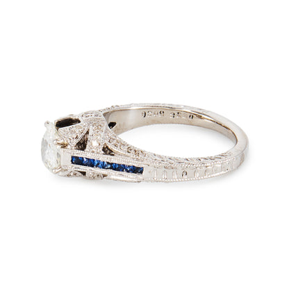 Magnificent 14ct white gold ring, set with a 0.70ct Old-European-Cut diamond, as well as seven princess-cut sapphires on each shoulder. The ring also features a diamond encrusted gallery. A valuation from The Gem Lab is included.