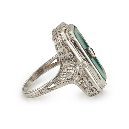 A very unusual 14ct white gold swivel ring set with a cameo of a woman wearing a diamond necklace on one side, and a green chrysoprase disc centred by a diamond on the other side. The versatile centre piece is surrounded by intricate filigree detail.