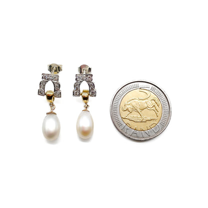 Stunning pair of 18ct white and yellow gold dangling earrings, each set with six small diamonds and a pearl drop.
