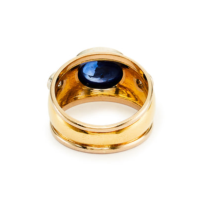 Glamorous 18ct yellow and white gold ring tube-set with a centre cabochon sapphire and a diamond on each side.