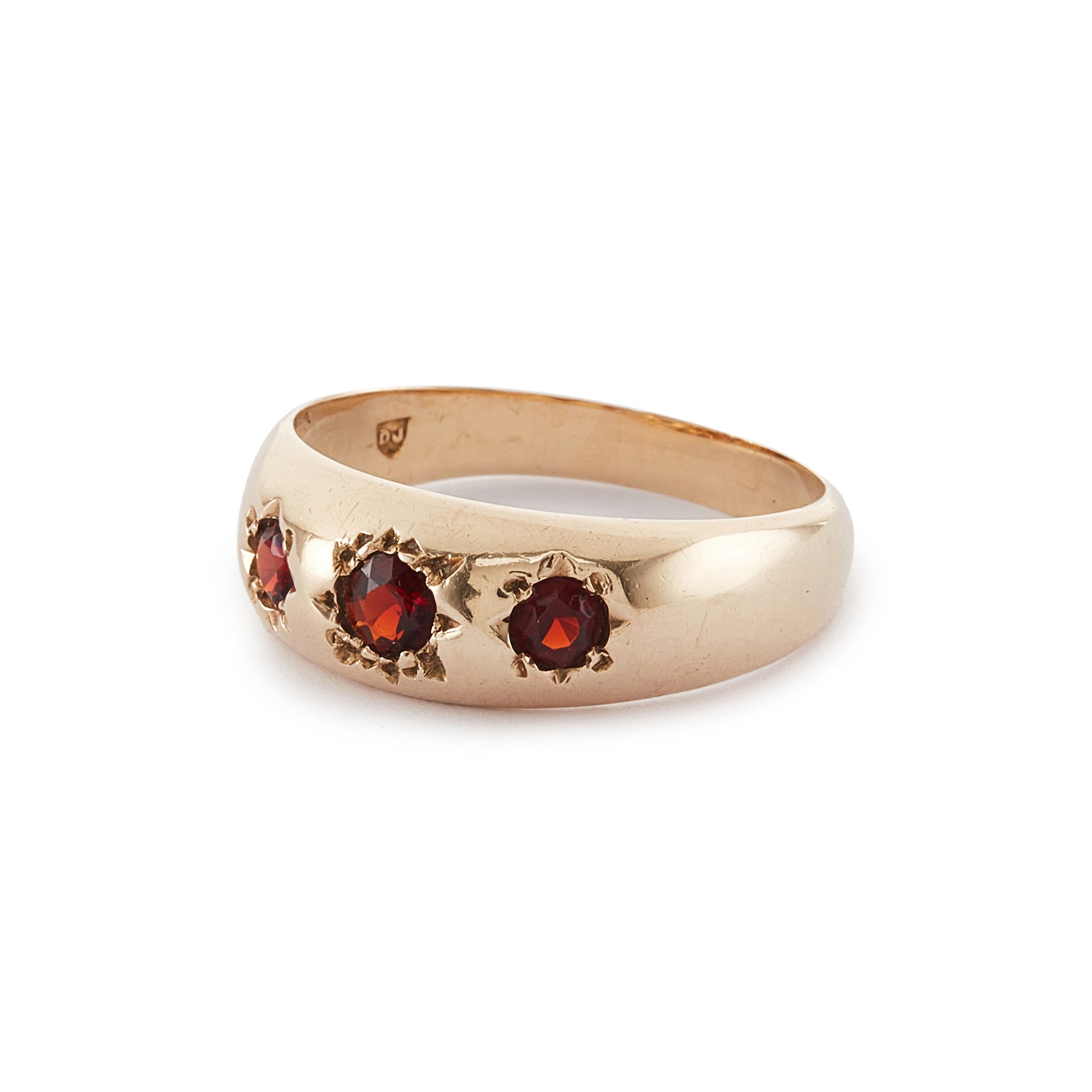 Classic 9ct gold gypsy ring set with three faceted garnets, each in a star setting.
London 1976.