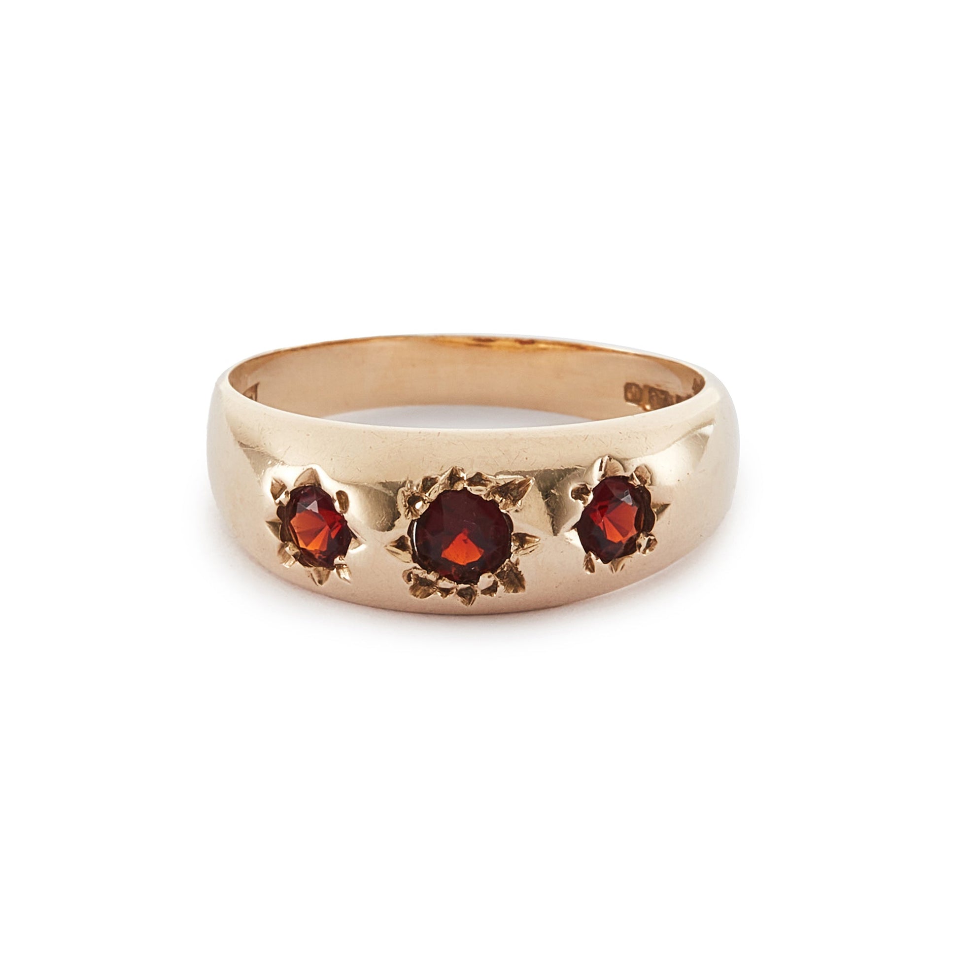 Classic 9ct gold gypsy ring set with three faceted garnets, each in a star setting.
London 1976.