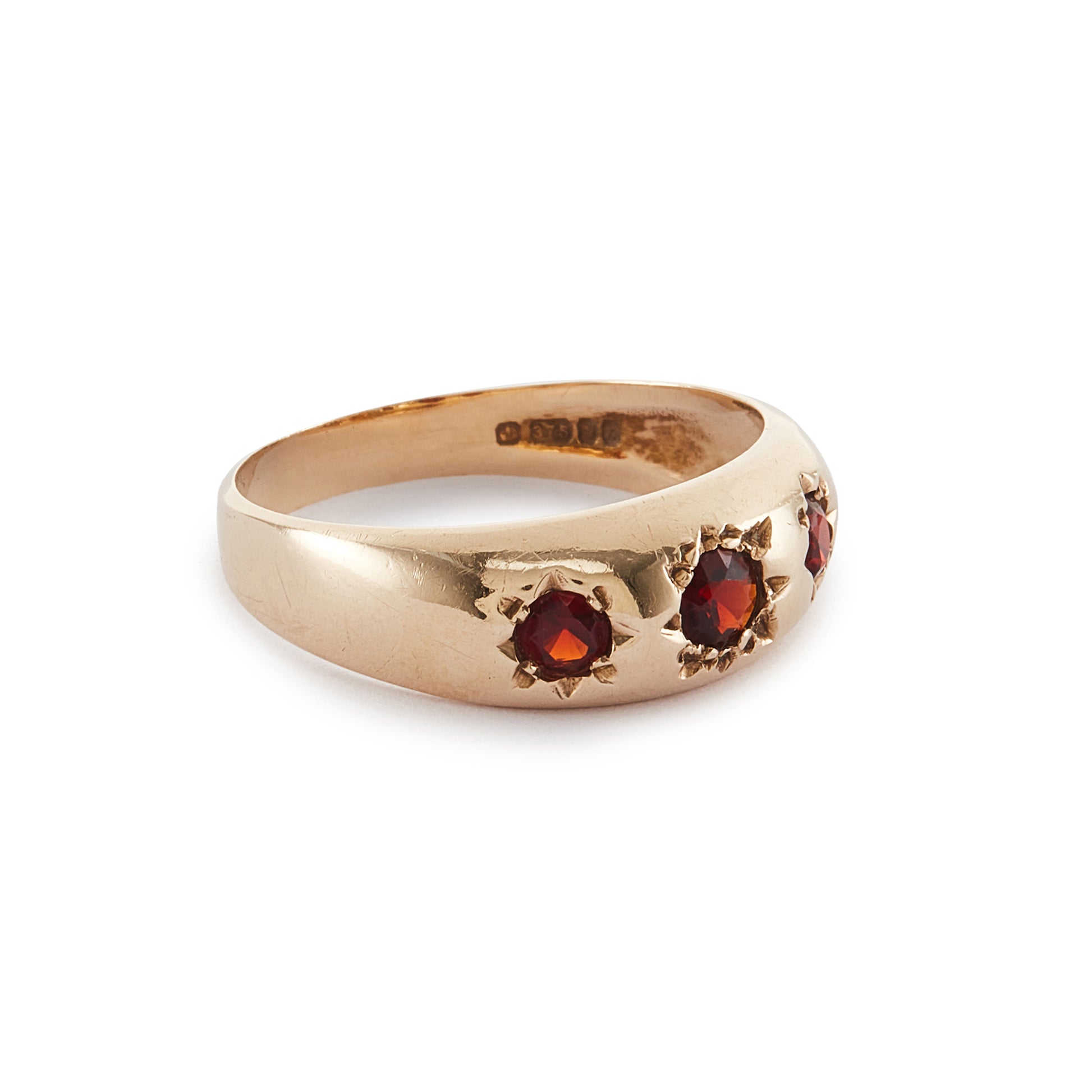 Classic 9ct gold gypsy ring set with three faceted garnets, each in a star setting.
London 1976.
