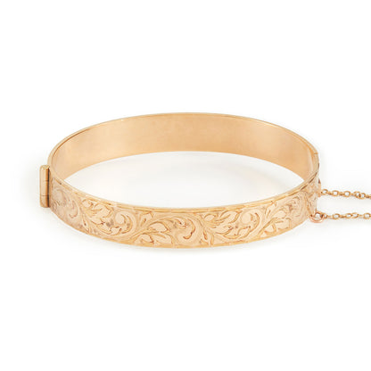 Beautifully engraved 9ct gold metal core bangle. Hinge clasp with safety chain attached.