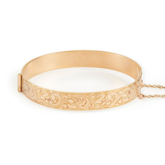 Beautifully engraved 9ct gold metal core bangle. Hinge clasp with safety chain attached.