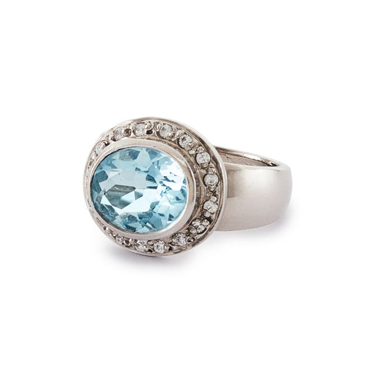 Stunning 9ct white gold ring set with a beautifully faceted blue topaz, surrounded by sixteen small round diamonds.