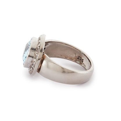 Stunning 9ct white gold ring set with a beautifully faceted blue topaz, surrounded by sixteen small round diamonds.