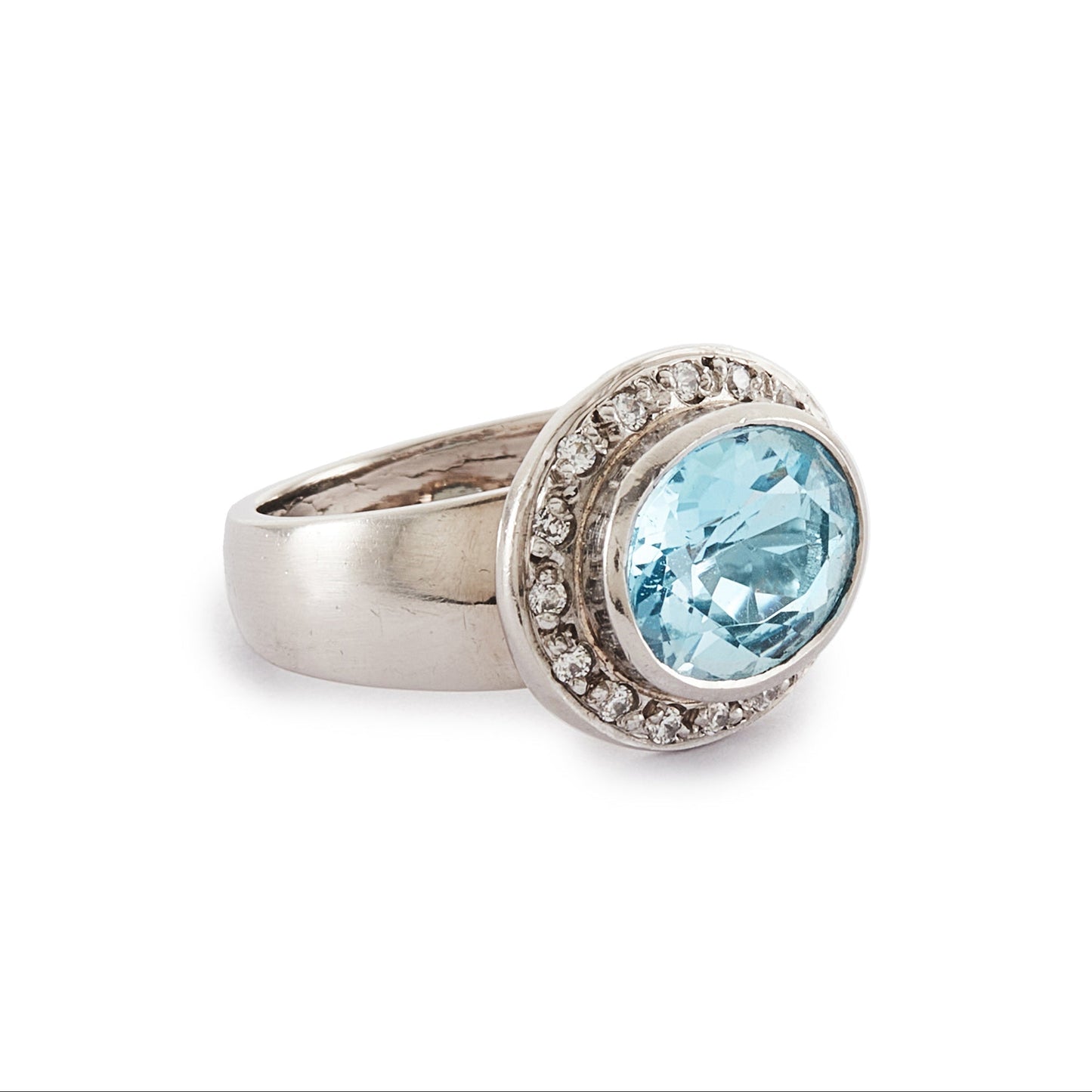 Stunning 9ct white gold ring set with a beautifully faceted blue topaz, surrounded by sixteen small round diamonds.