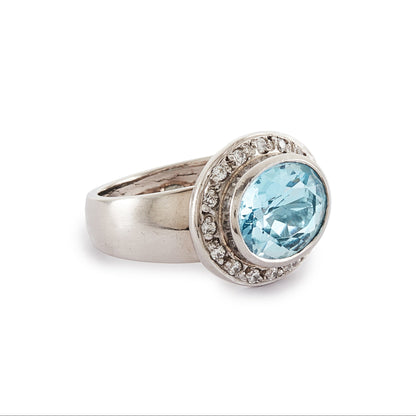 Stunning 9ct white gold ring set with a beautifully faceted blue topaz, surrounded by sixteen small round diamonds.