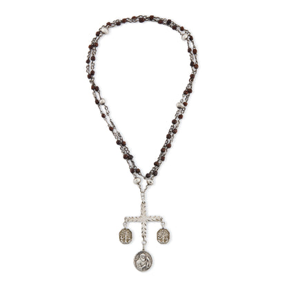 Stunning antique silver rosary with a cross and three dangling saint discs. The cross hangs on a 102cm oxidised silver ornate link chain, interspersed with natural red-brown stones and six silver bobbles.