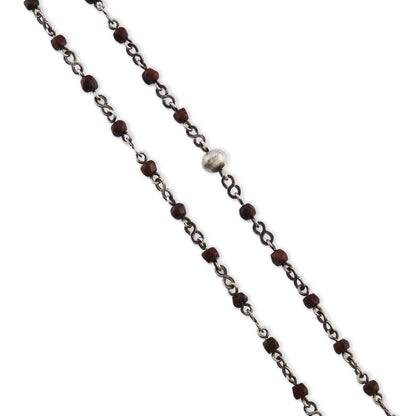 Stunning antique silver rosary with a cross and three dangling saint discs. The cross hangs on a 102cm oxidised silver ornate link chain, interspersed with natural red-brown stones and six silver bobbles.