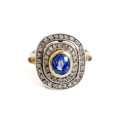 Beautiful Art Deco 14ct white and yellow gold ring set with an oval cornflower blue sapphire surrounded by two rows of small diamonds, as well as a small diamond on each shoulder. Italy