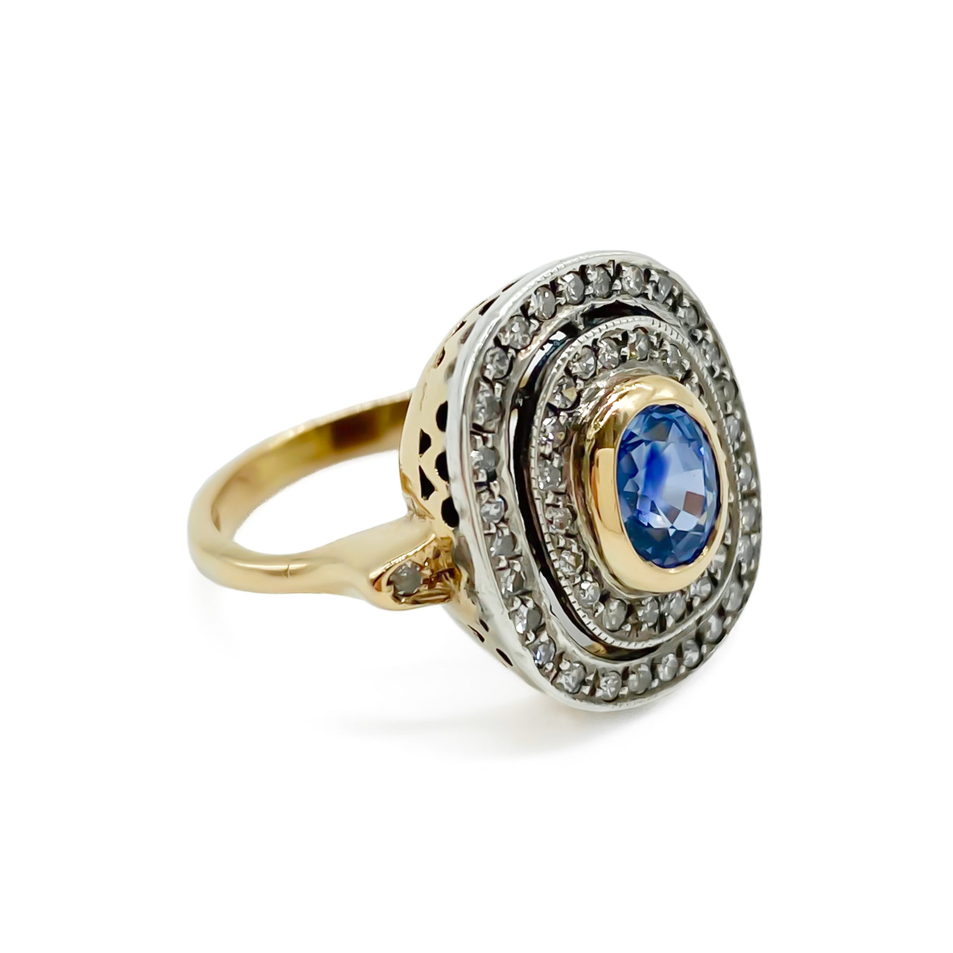 Beautiful Art Deco 14ct white and yellow gold ring set with an oval cornflower blue sapphire surrounded by two rows of small diamonds, as well as a small diamond on each shoulder. Italy