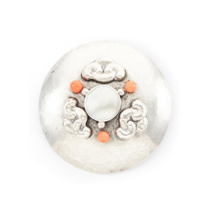 Large hand-beaten silver Arts and Crafts brooch set with a Mother of Pearl disc in the centre, surrounded by three coral beads and a repoussé design.