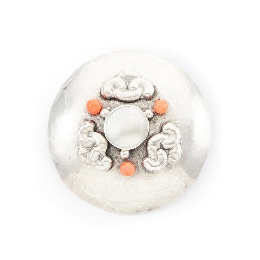 Large hand-beaten silver Arts and Crafts brooch set with a Mother of Pearl disc in the centre, surrounded by three coral beads and a repoussé design.