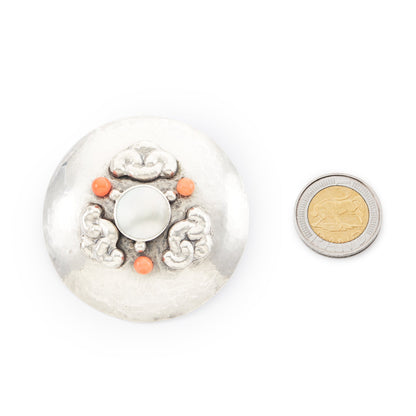 Large hand-beaten silver Arts and Crafts brooch set with a Mother of Pearl disc in the centre, surrounded by three coral beads and a repoussé design.