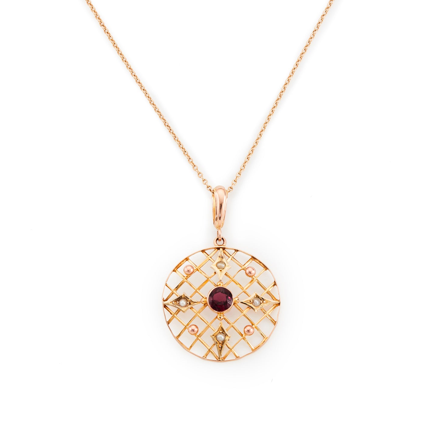 Delicate Edwardian 9ct gold pendant with a faceted almandine garnet and four seed pearls, in an intricate circular setting.