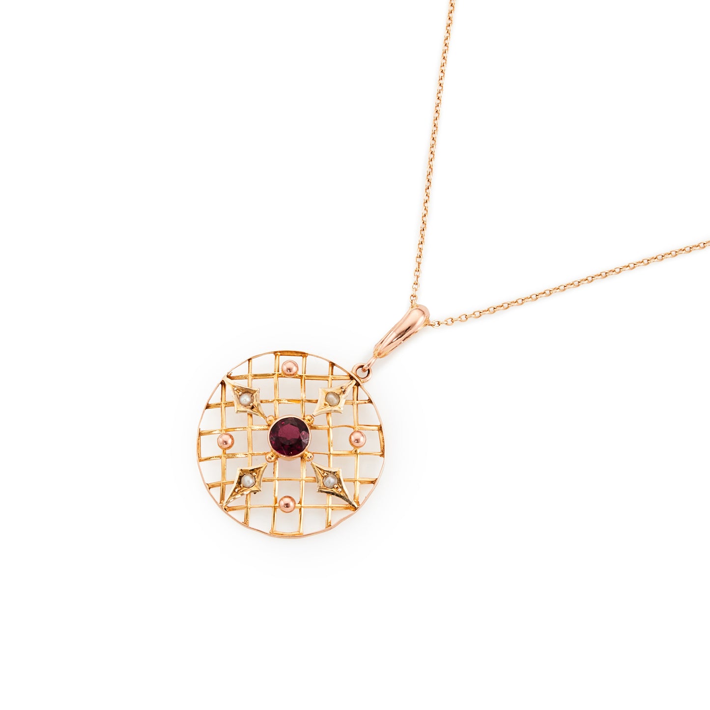 Delicate Edwardian 9ct gold pendant with a faceted almandine garnet and four seed pearls, in an intricate circular setting.