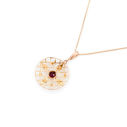 Delicate Edwardian 9ct gold pendant with a faceted almandine garnet and four seed pearls, in an intricate circular setting.