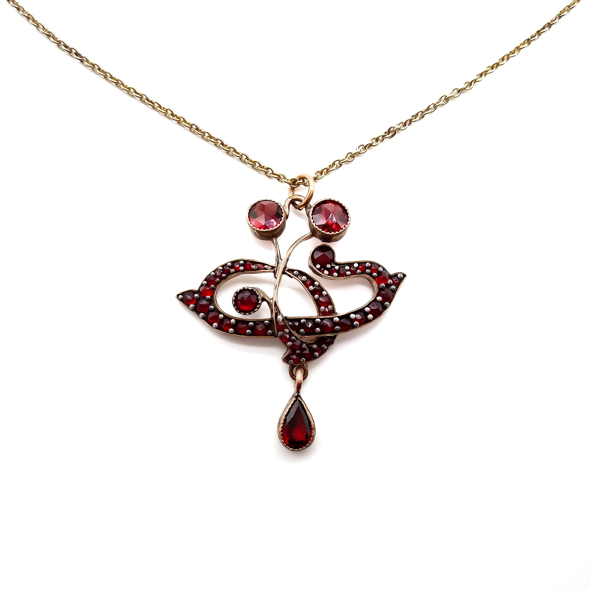 Delicate Edwardian pendant set with deep red Bohemian garnets on a silver gilt chain.