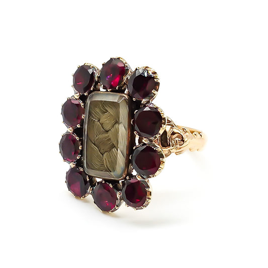 Stunning Georgian mourning ring in a 15ct yellow gold setting with plaited hair under bevelled glass, surrounded by ten beautiful deep red flat cut garnets. Later shank with lovely engraving.