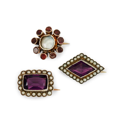 Lot of three quaint silver/silver gilt miniature brooches set with purple paste stones, garnets and seed pearls. Lovely to be worn as a group or individually.