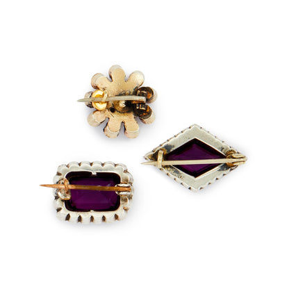 Lot of three quaint silver/silver gilt miniature brooches set with purple paste stones, garnets and seed pearls. Lovely to be worn as a group or individually.