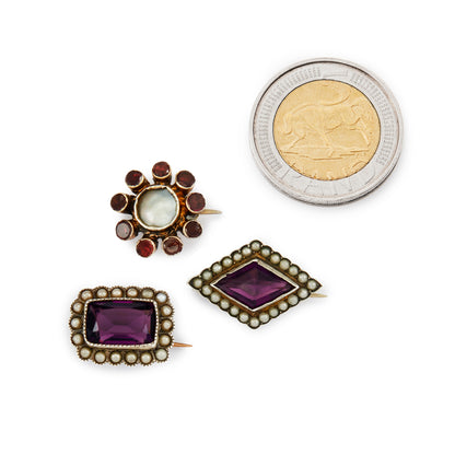 Lot of three quaint silver/silver gilt miniature brooches set with purple paste stones, garnets and seed pearls. Lovely to be worn as a group or individually.