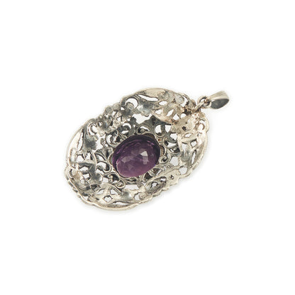 Regal silver pendant set with a large, beautifully faceted purple amethyst stone, surrounded by  eight small amethysts in an intricate design.