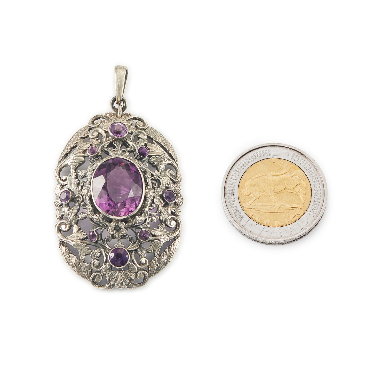 Regal silver pendant set with a large, beautifully faceted purple amethyst stone, surrounded by  eight small amethysts in an intricate design.