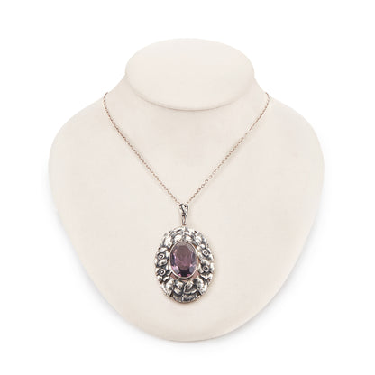 Very ornate oval pendant with a beautifully faceted purple amethyst in a floral setting, on a silver chain. 800 Silver. German