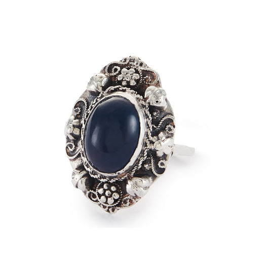 Lovely silver Arts and Crafts ring set with a cabochon sodalite, surrounded by intricate floral detail.
