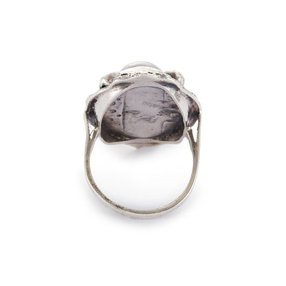 Lovely silver Arts and Crafts ring set with a cabochon sodalite, surrounded by intricate floral detail.