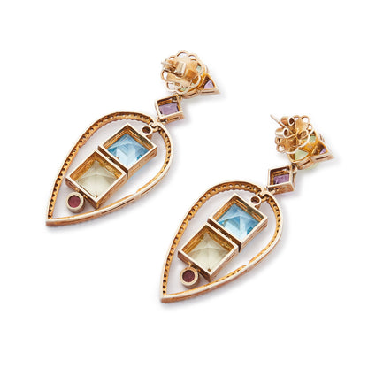 Glamorous antique-inspired silver-gilt pendant earrings set with a variety of faceted semi-precious gemstones (amethyst, green agate, blue topaz, citrine, pink tourmaline) in a geometric design. Unknown designer. London.