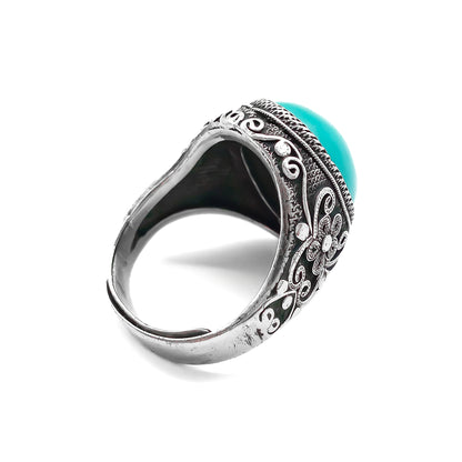 Silver ring set with a beautiful cabochon turquoise stone and ornate filigree embellishment. 